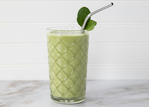 Green smoothie in a glass with a straw